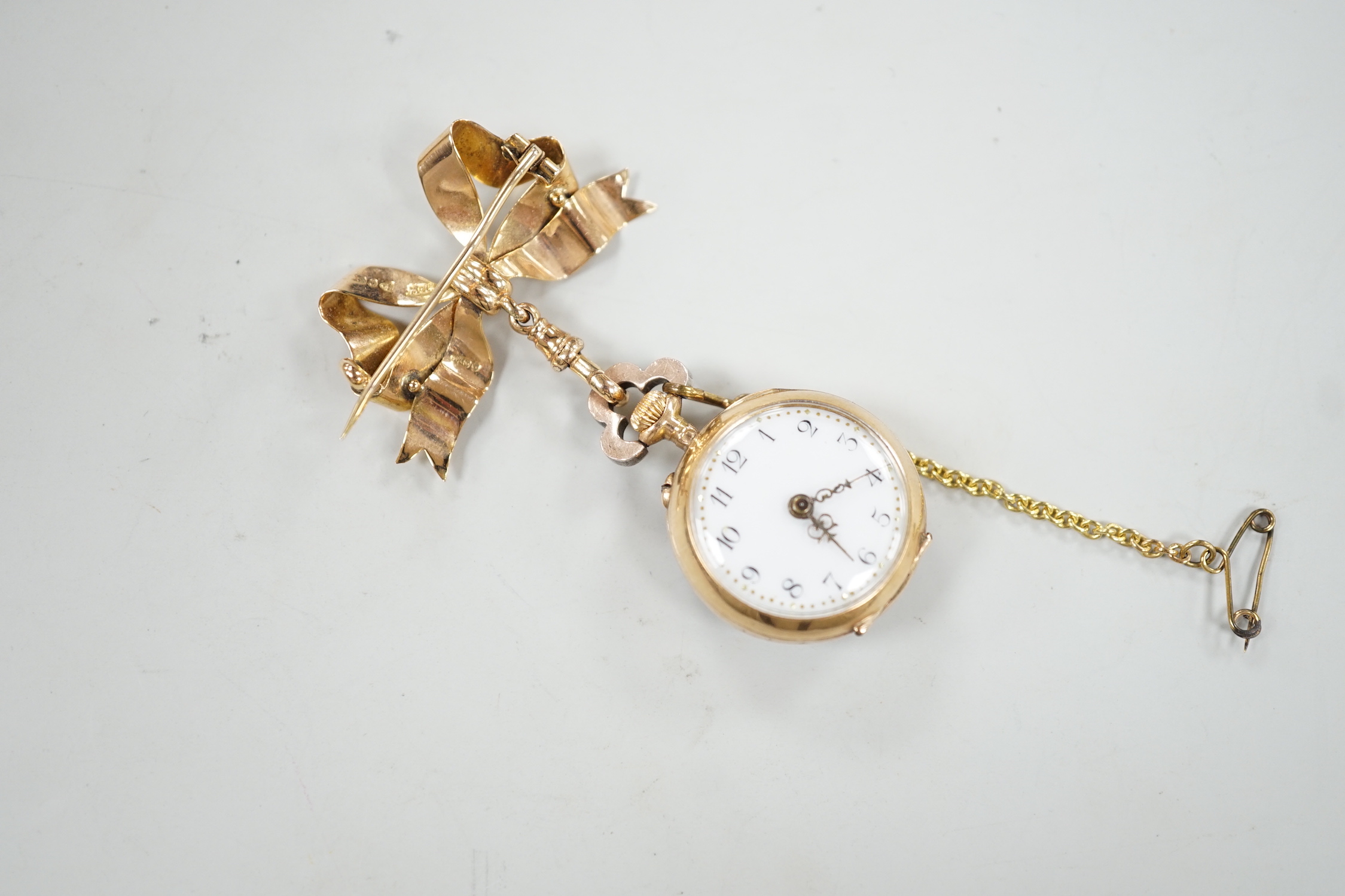 A lady's late 19th century French? yellow metal, emerald and rose cut diamond cluster set fob watch, diameter 24mm, suspended from a late Victorian 9ct gold ribbon bow brooch, gross weight 17.1 grams.